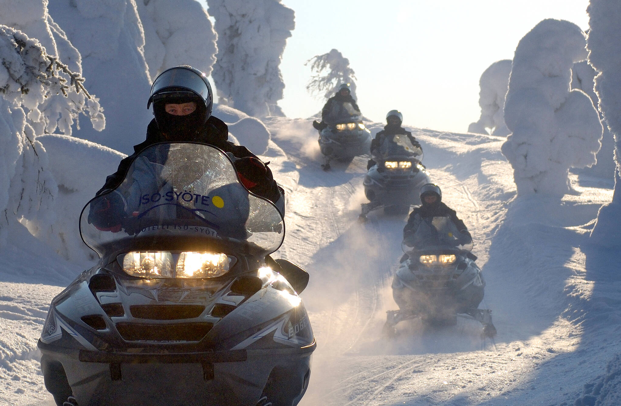 Group of people driving snowmobiles in a snowy landscape