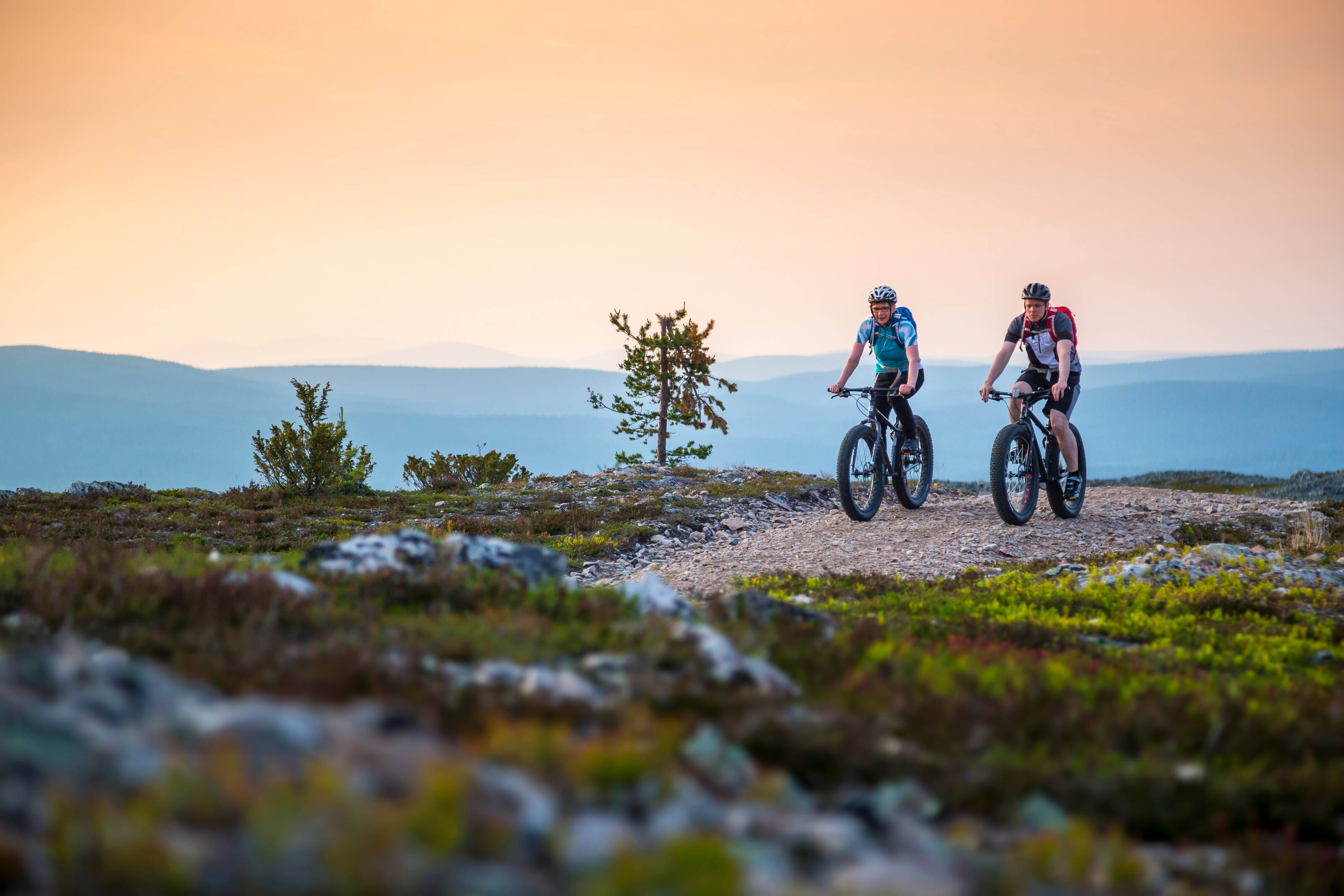 Two people mountain biking in Lapland under the midnight sun.