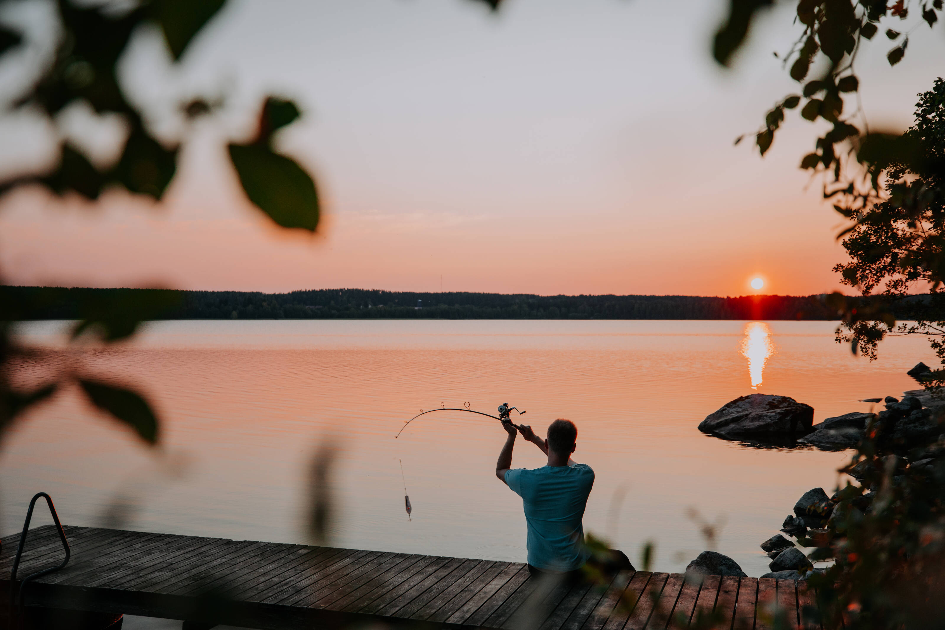 A man casts a fishing line from the dock during a Lake Lehmonkarki sunset.