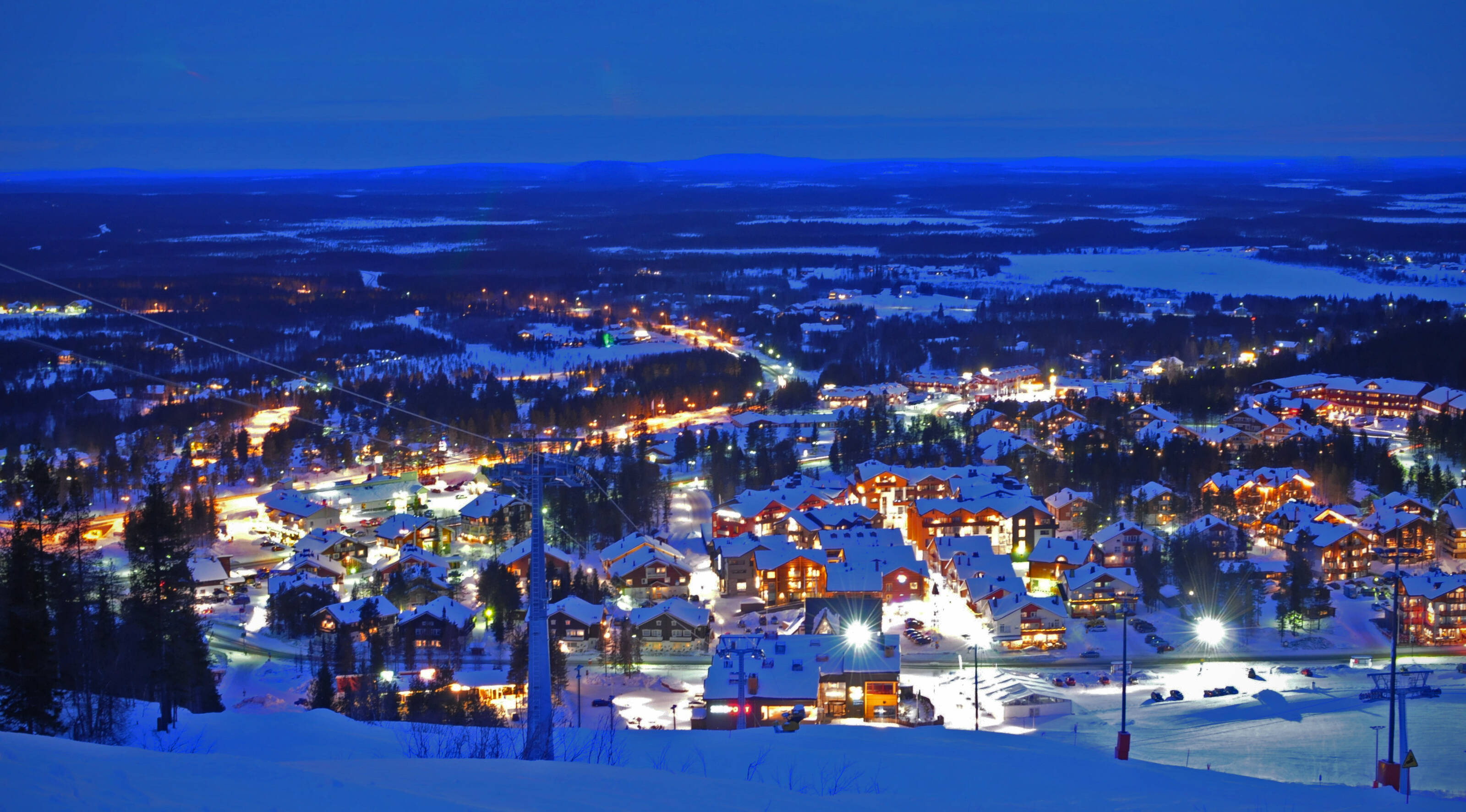 An aerial view of the square full of aurora cabins in the middle of snow-covered forest.