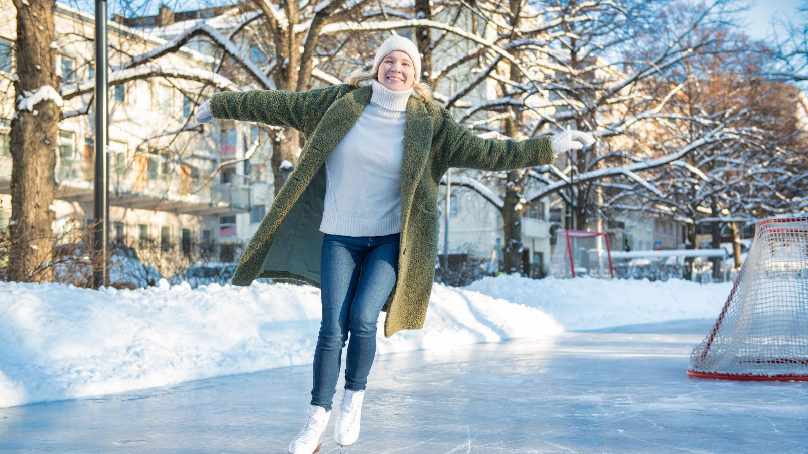 Woman smiling to the camera while skating on a sunny winter day.