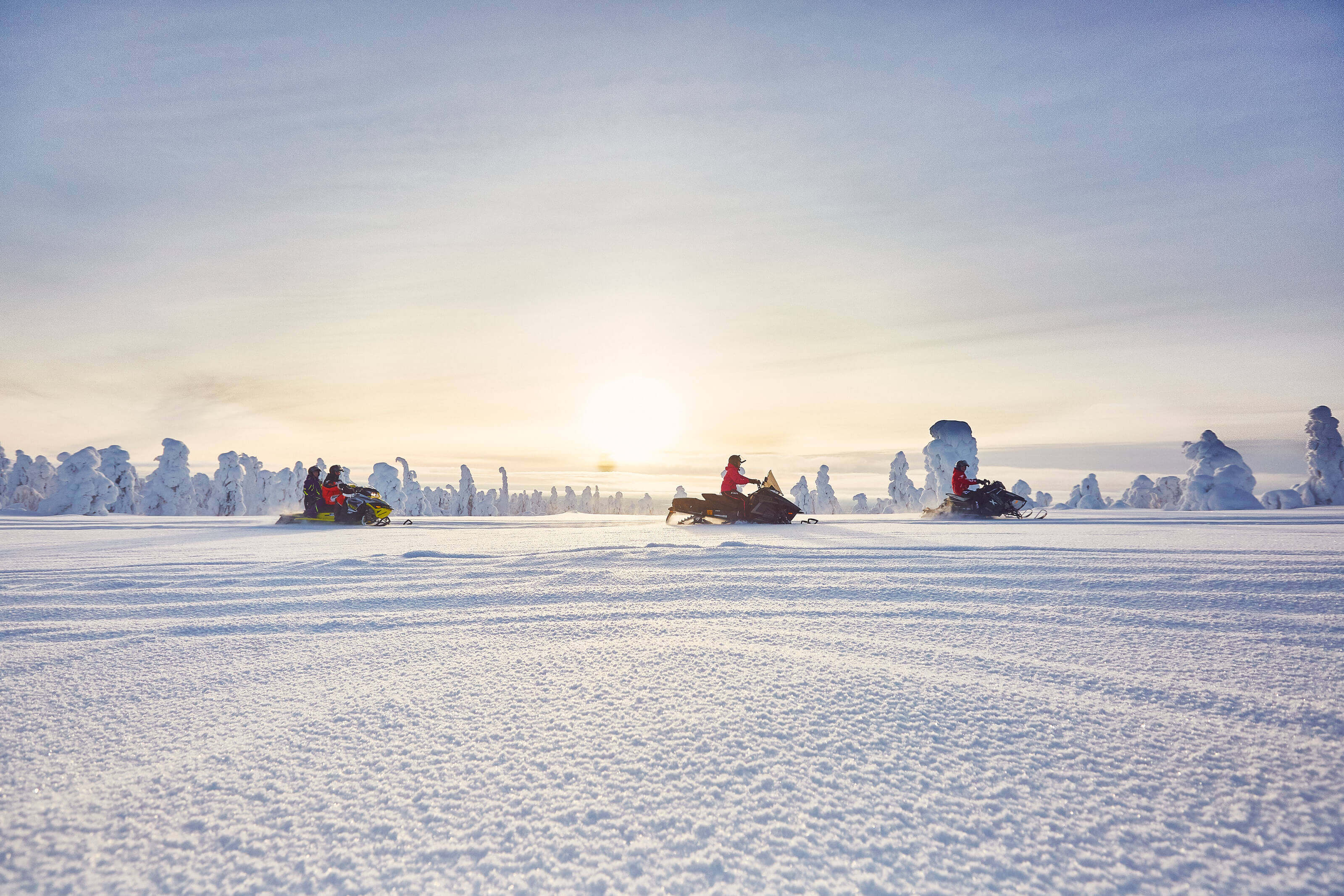 A snowmobile caravan crossing a snow-covered fields in the Finnish Lapland