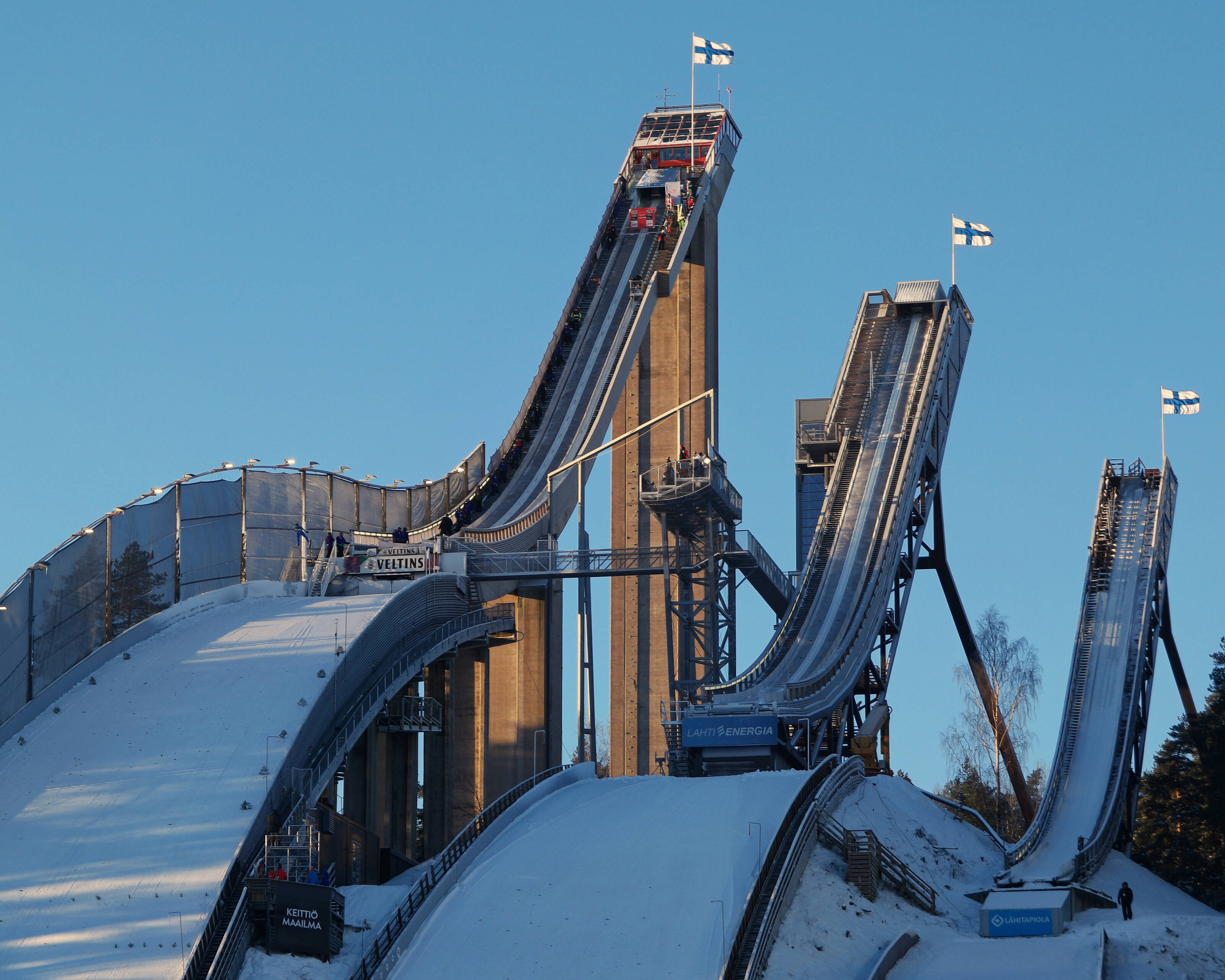 Three snow-covered ski jumping towers standing in a row.