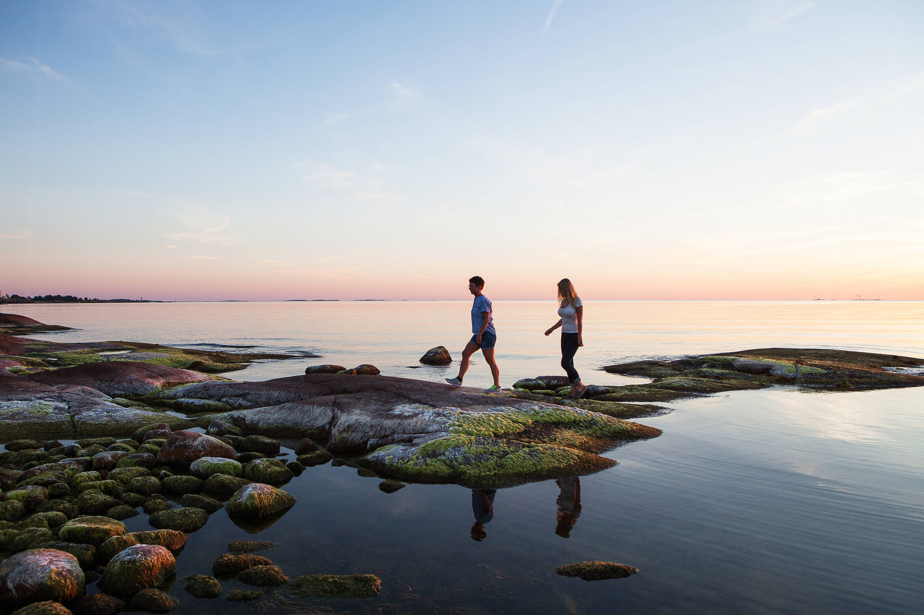 Two people walking on stones by the sea shore