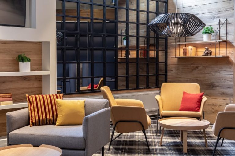 The lobby area at the Scandic Pasila hotel, which includes modern, wood-paneled walls and an array of gray and yellow armchairs.