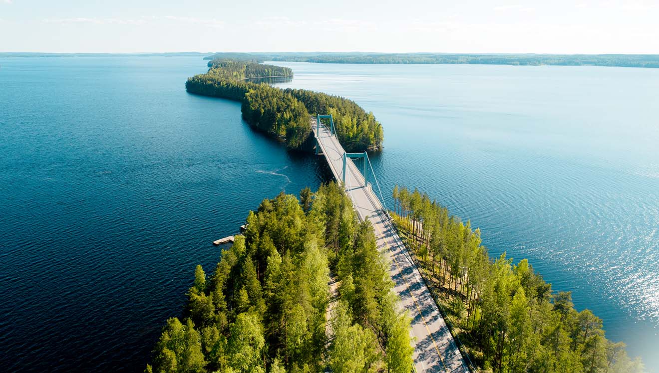 A bird view of forest along the road in the middle of the lake in Lahti