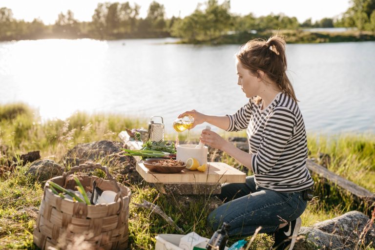 A woman cooking on the shores of a lake.