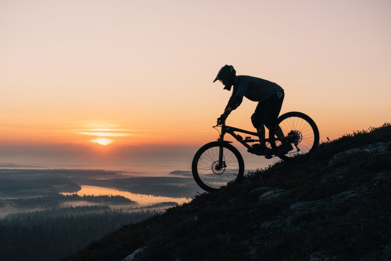Silhouette of a person riding a mountain bike downhill