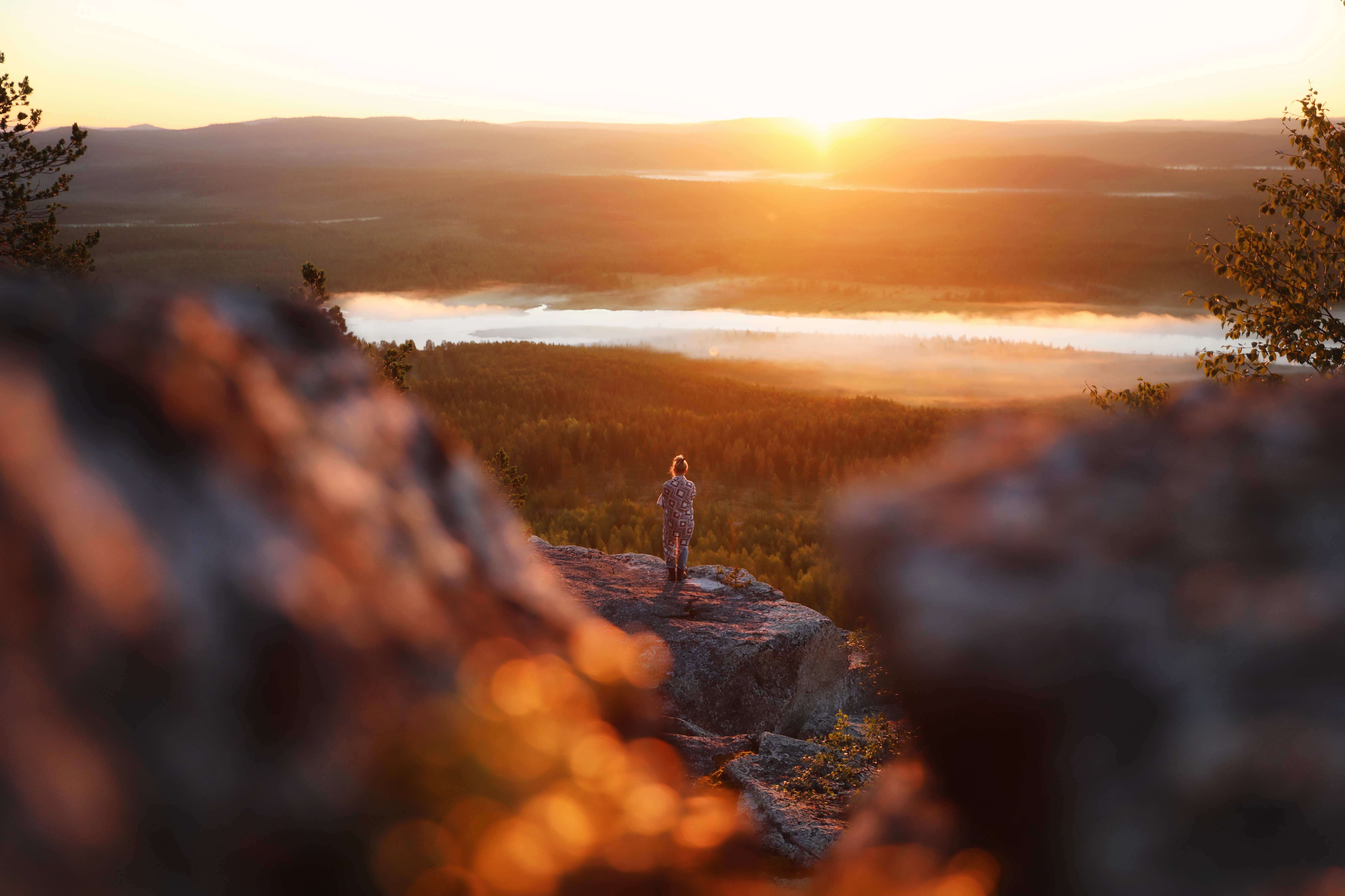 Girl admiring the midnight sun on a cliff in Lapland