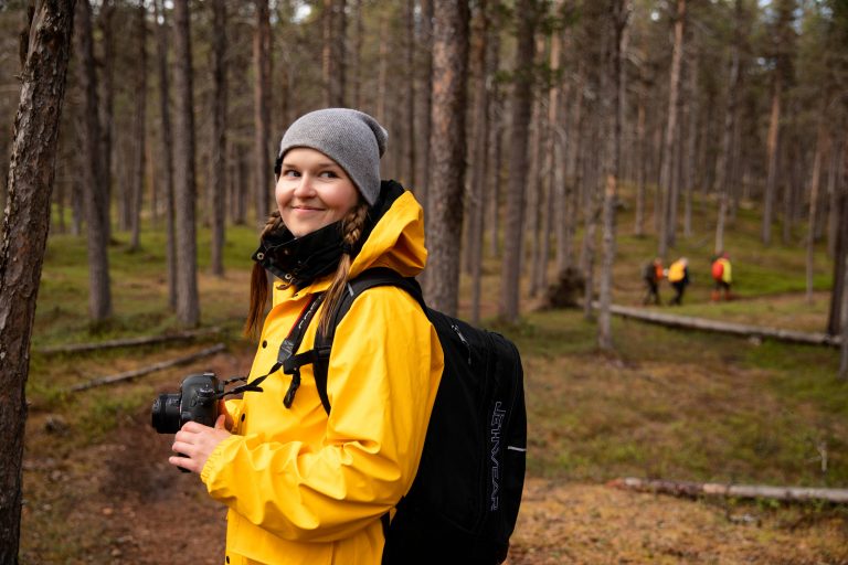 A woman with a camera in the forest.